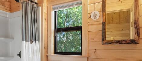 A wooden cabin bathroom with a toilet, sink, and shower.