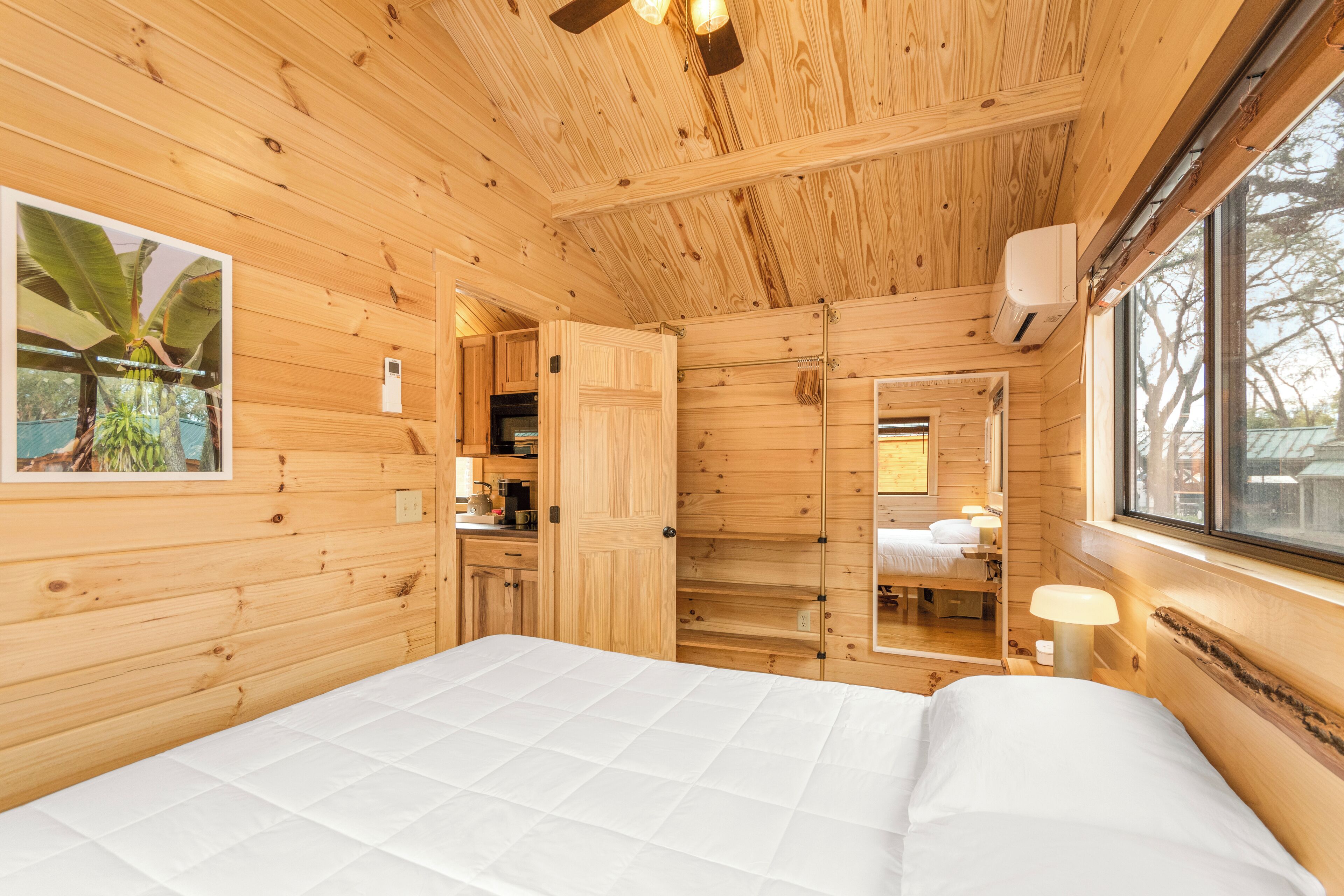 Une pièce de style cabane en bois, avec un lit, une fenêtre et un miroir.