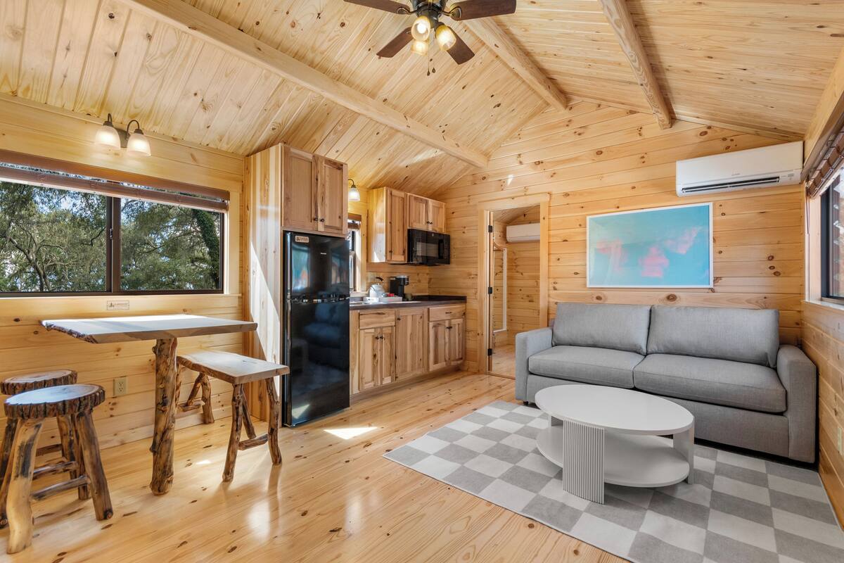 A wooden cabin interior with a kitchen, dining area, and living room.