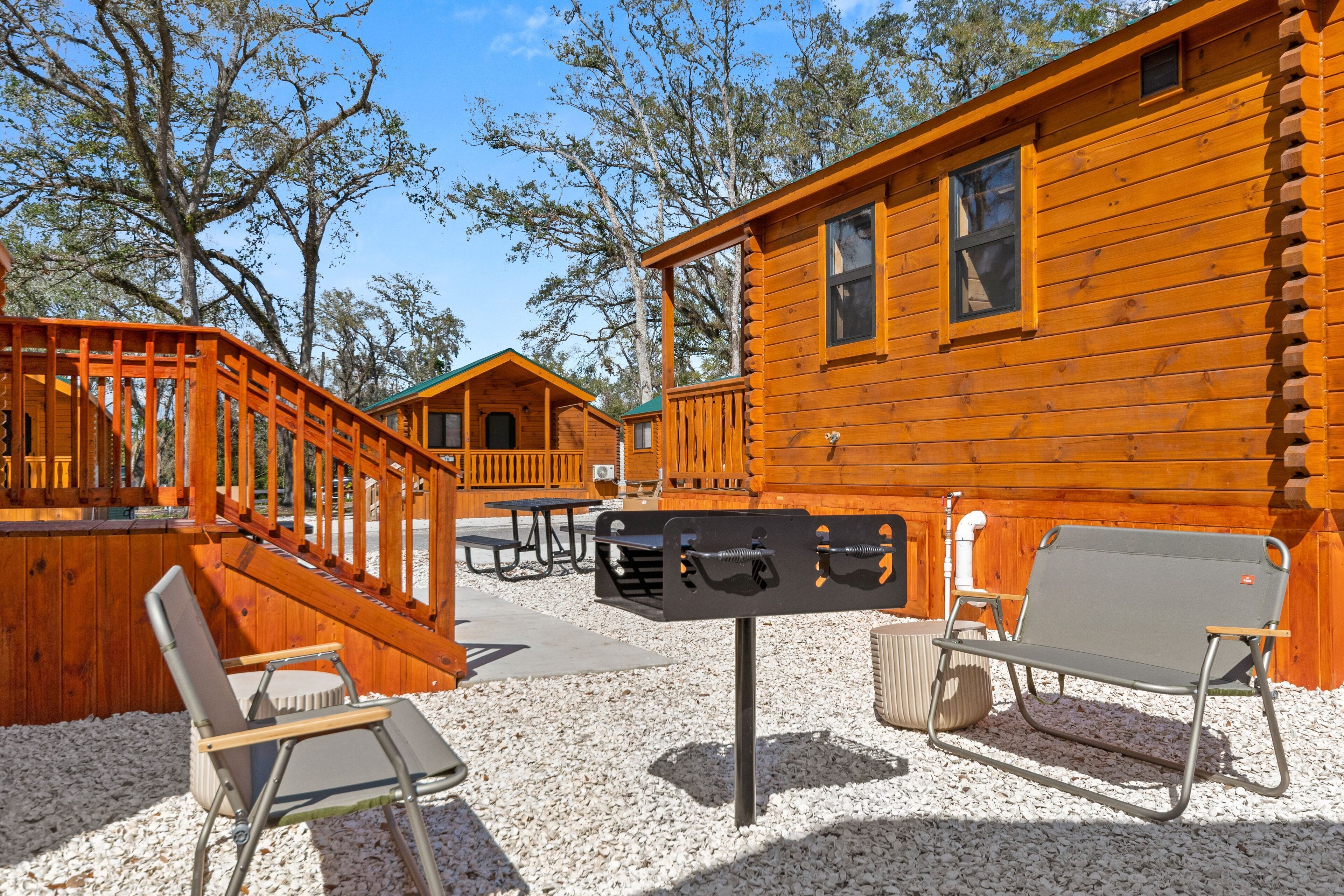 A wooden cabin with a deck, outdoor seating, and a picnic table.