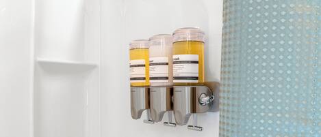 A bathroom with a wall-mounted soap dispenser and a shower curtain.