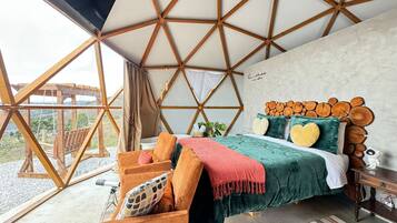 Une chambre avec un plafond en bois aux motifs géométriques, un lit doté d’une tête de lit en bois et une vue sur l’extérieur.