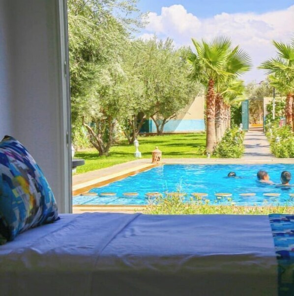 Relax by the serene pool surrounded by lush greenery and palm trees.