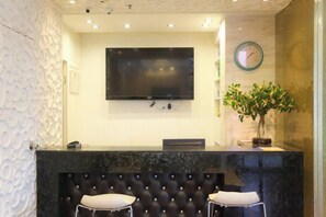Een receptie met een flatscreen televisie, een klok en een potplant.