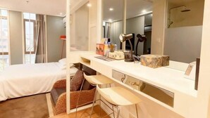A hotel room with a bed, a desk with a mirror, a shower, and a view of the city. - Nantong White-collar INN (Nantong)