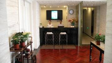 A reception area with a reception desk, two bar stools, a television, and a clock on the wall.