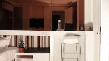 A modern hotel room with a bed, a TV, a small table, and a chair.