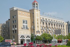 Un edificio de varios pisos con una torre de reloj, ventanas grandes y señalización que indica que es un hotel.