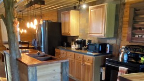 A rustic kitchen with wooden cabinets, a built-in island, and a stove.