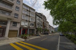 A residential street with multi-story buildings, a clear road, and parked cars. - yiranju (Yueqing)
