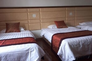 A hotel room with three beds arranged in a row, each with a headboard and pillows. - yiranju (Yueqing)