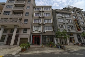 A multi-story building with a central entrance, balconies, and air conditioning units. - yiranju (Yueqing)