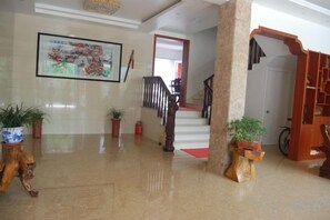 A lobby with a staircase, potted plants, and a framed artwork on the wall. - yiranju (Yueqing)
