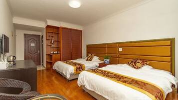 A hotel room with two beds, a desk, a television, and a wardrobe.