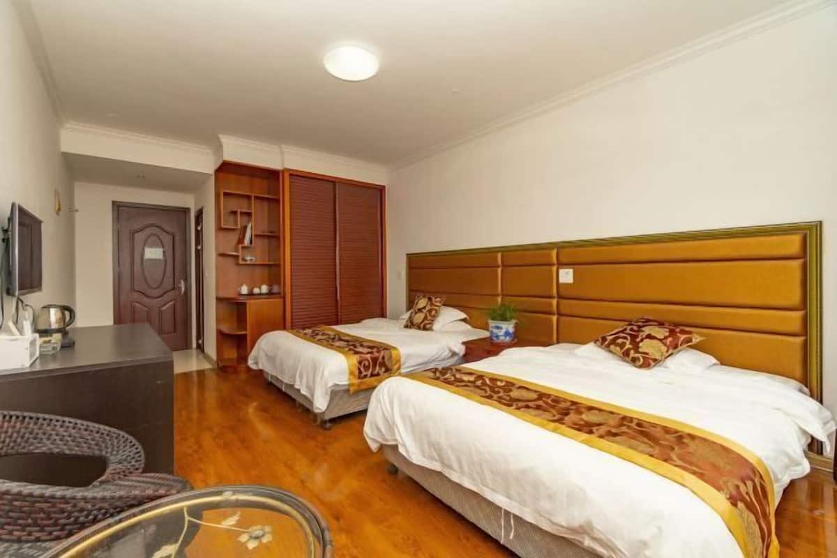 A hotel room with two beds, a desk, a chair, and a wardrobe.
