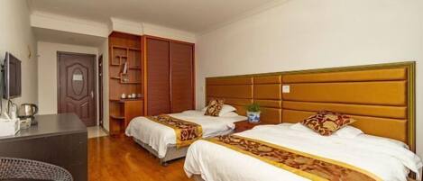 A hotel room with two beds, a desk, a chair, and a wardrobe.