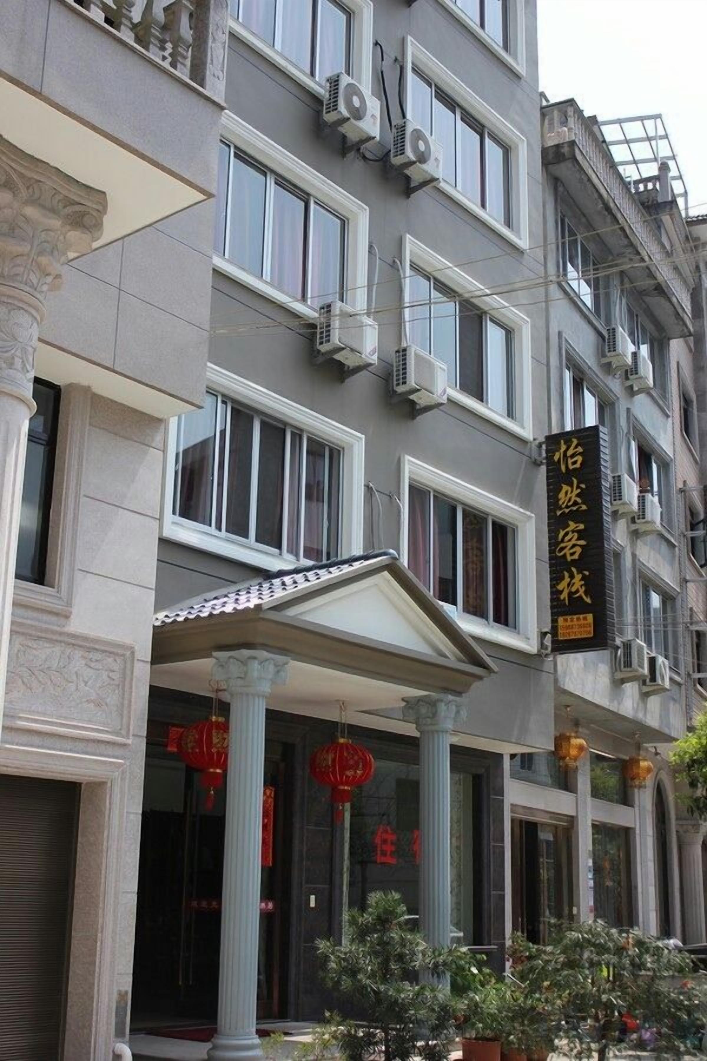 A multi-story building with a classical architectural style, featuring columns and a balcony.