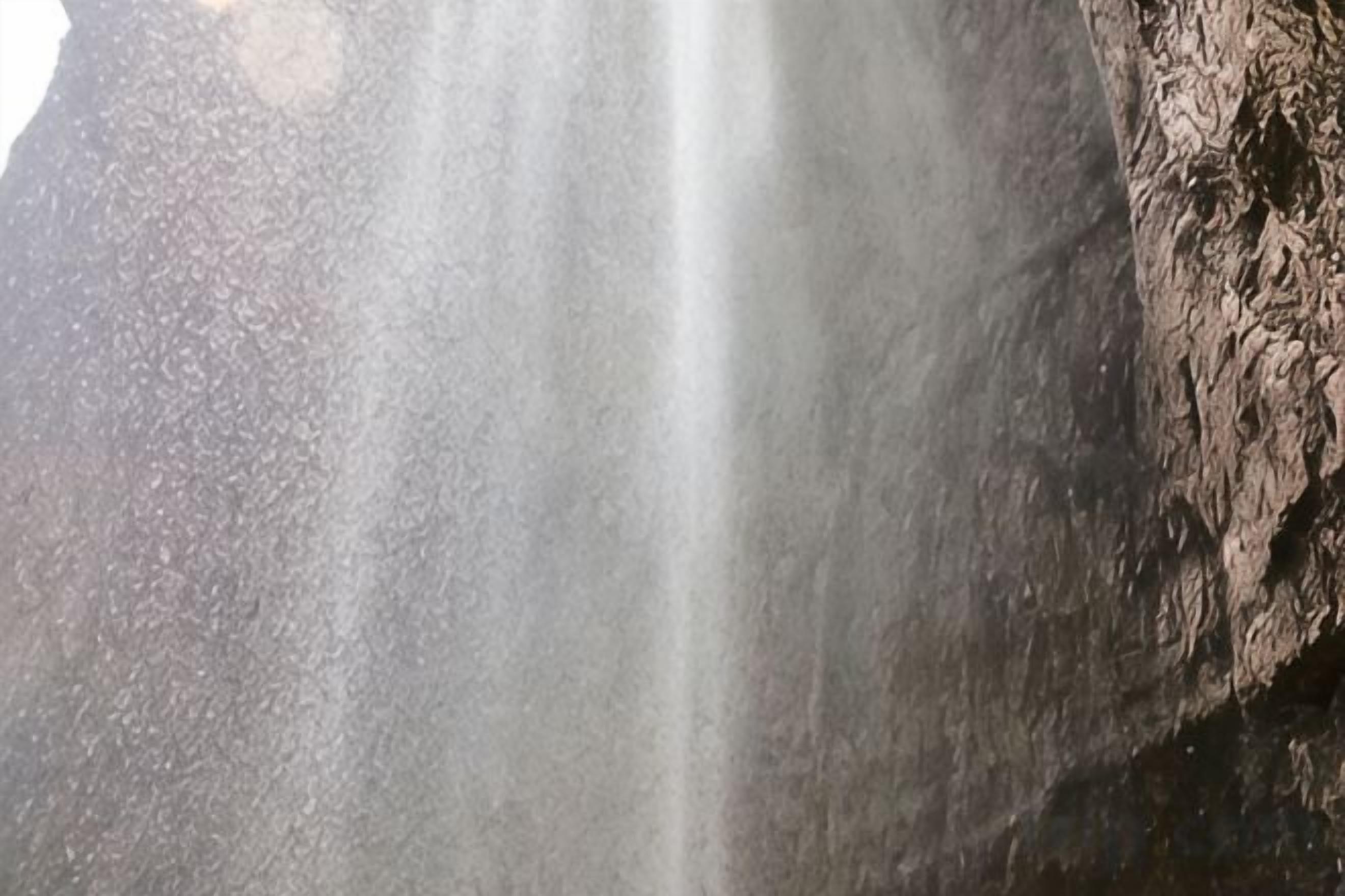 A close-up of a rock surface with a water stream flowing over it.