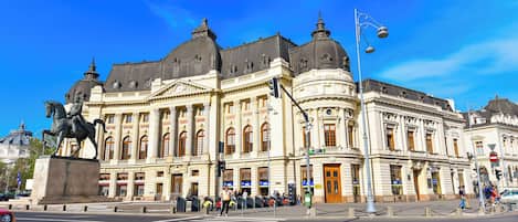 En historisk byggnad med klassisk arkitektur, stora fönster och en framträdande staty.