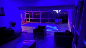 Ein modernes Wohnzimmer mit Pool, bequemen Sitzgelegenheiten und großen Fenstern.