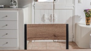 Une cuisine avec des meubles blancs, une chaise en bois, une planche à découper avec du fromage et des raisins, et une machine à café.