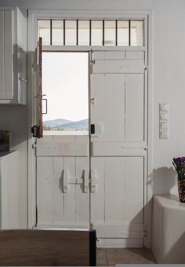 A white door with a window, a light switch, and a small vase with flowers.