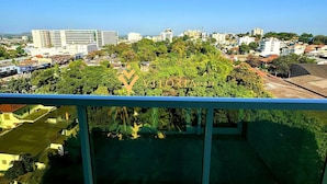 Un balcón con vistas a un paisaje urbano, que incluye edificios y áreas verdes.