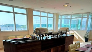 Una cocina moderna con ventanas amplias, una isla central con parrilla y un espacio de estar con sillas amarillas.