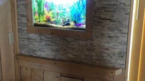 A wooden-framed aquarium with a brick-patterned wall behind it.