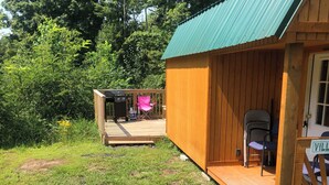 A wooden cabin with a deck, a picnic table, and a grill.
