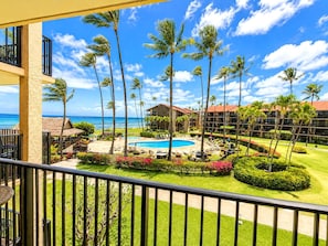 A resort with a pool, palm trees, and a view of the ocean.