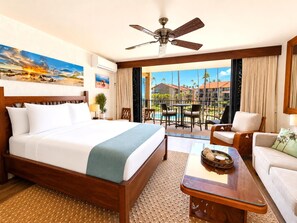 Ein Hotelzimmer mit Bett, Deckenventilator, Balkon mit Tisch und Stühlen sowie Blick ins Freie.