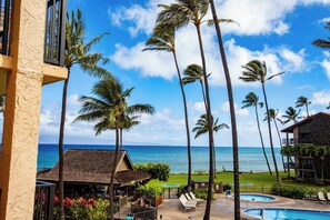 A resort with a pool, palm trees, and a view of the ocean.