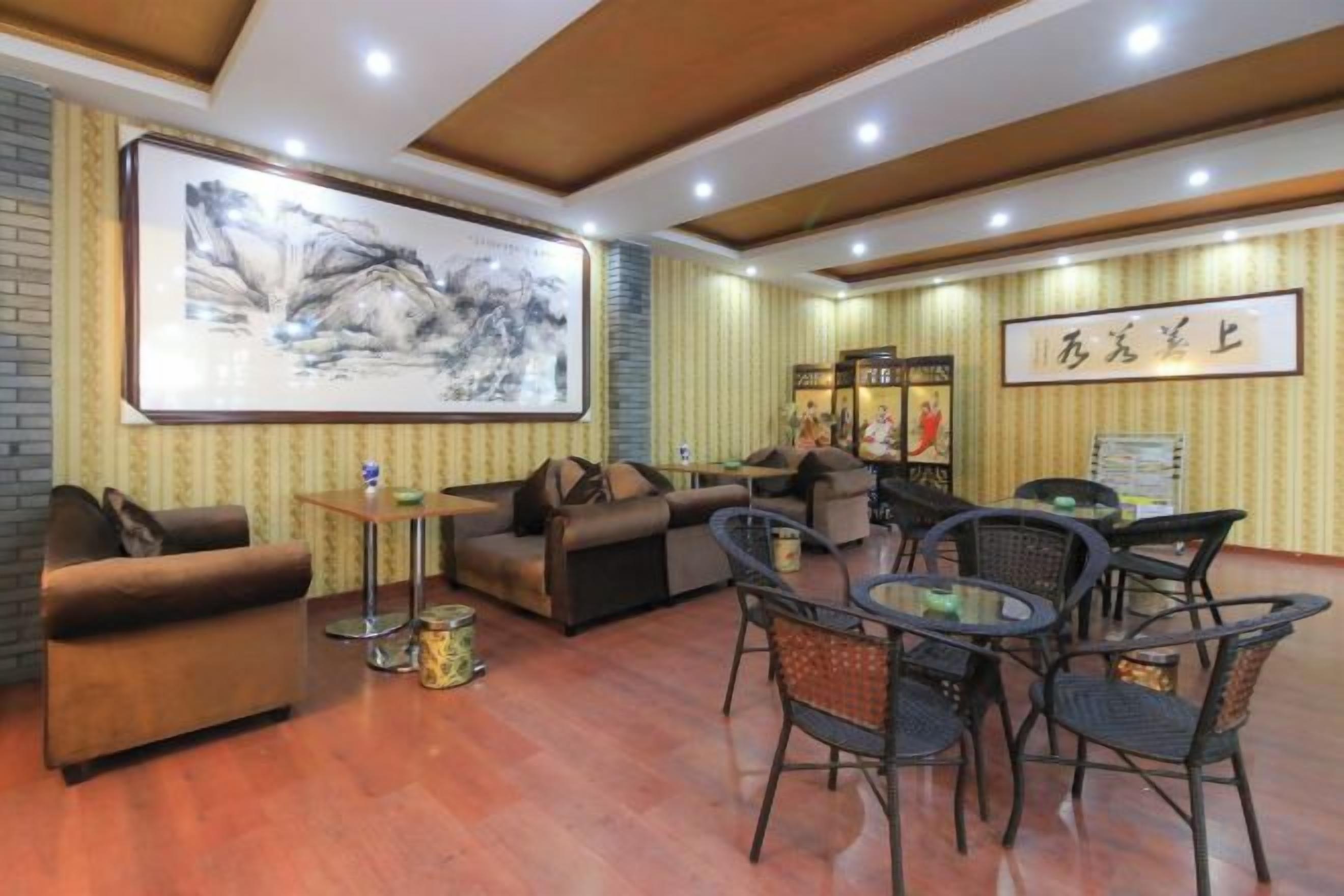 A hotel lobby with a sofa, chairs, a coffee table, and a large framed artwork on the wall.