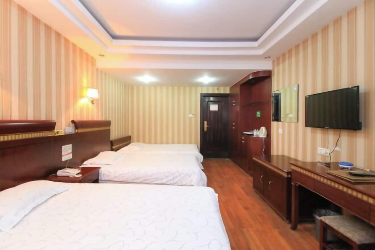 A hotel room with two beds, a desk, a TV, and a mirror.