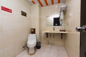 A small, clean bathroom with a toilet, sink, and mirror. There is a trash can next to the toilet and a small shelf with a towel. - Garden of Garden Hotel (Dongyang)