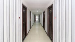 A long, narrow hallway with white striped walls and wooden doors on either side.