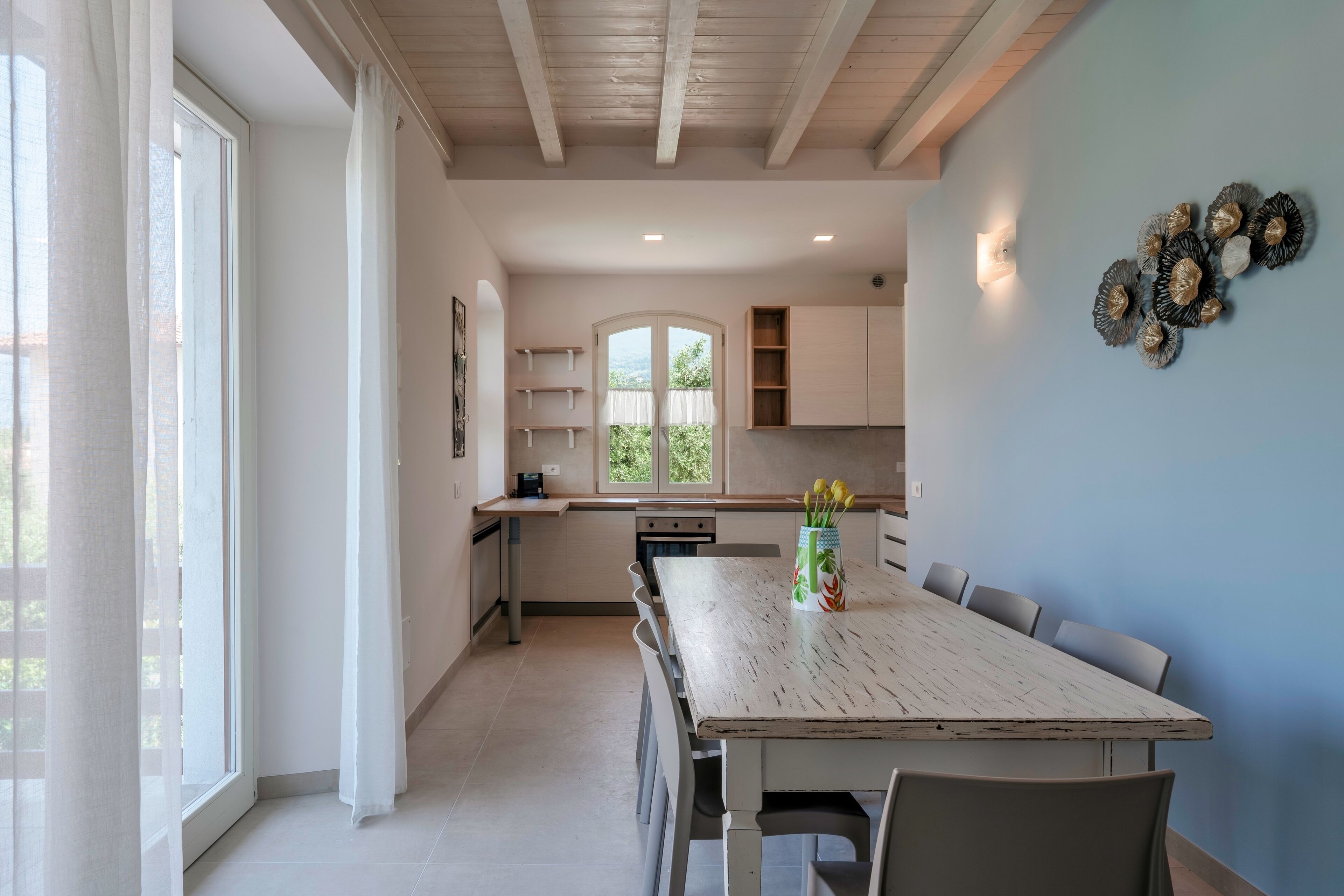 Una cocina moderna con una mesa de comedor grande, armarios blancos y vistas a través de una ventana.