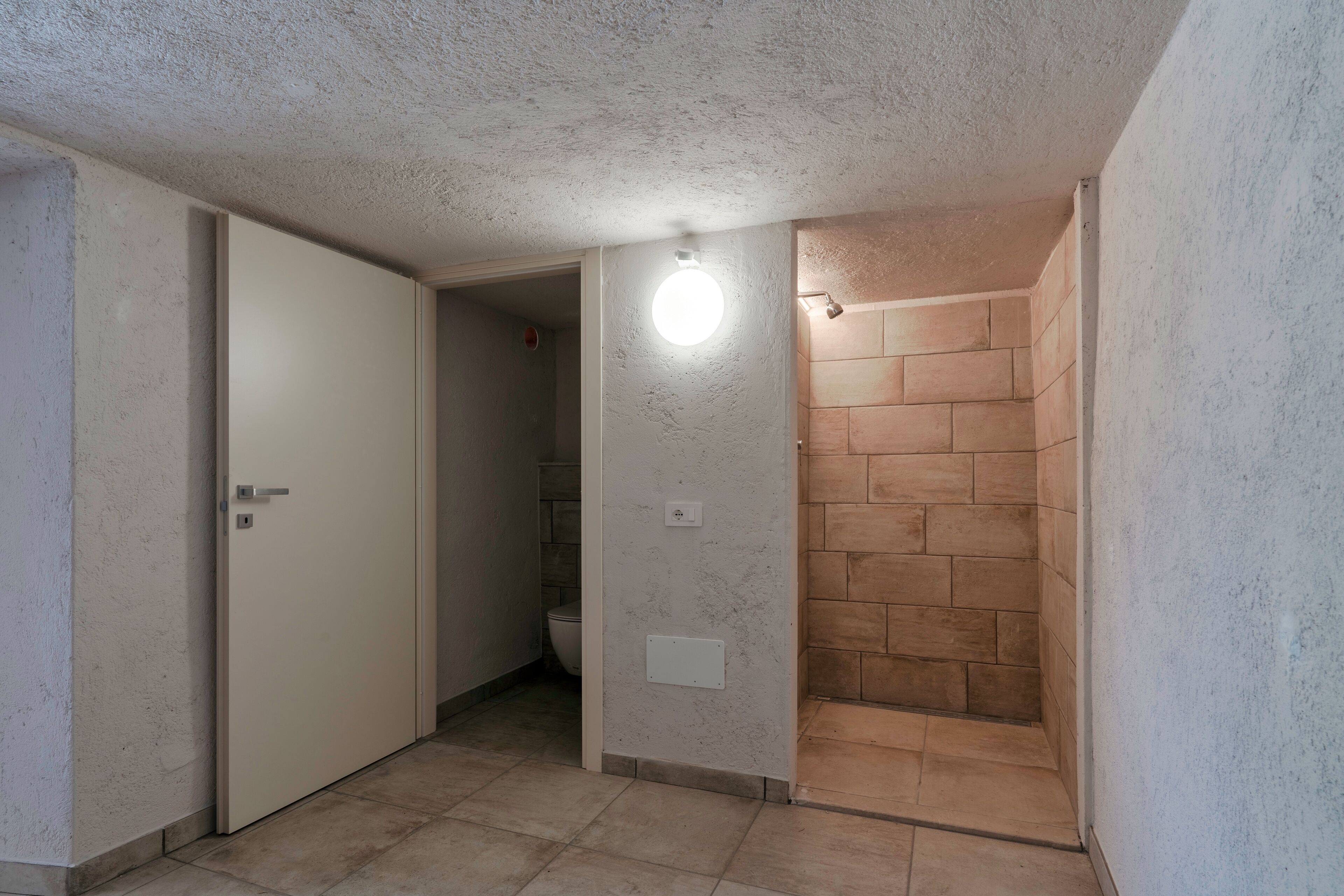 A bathroom with a shower, a toilet, and a door.