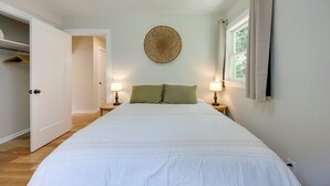 Een slaapkamer met een groot bed, twee bedlampen, een ronde wanddecoratie en een raam met gordijnen.