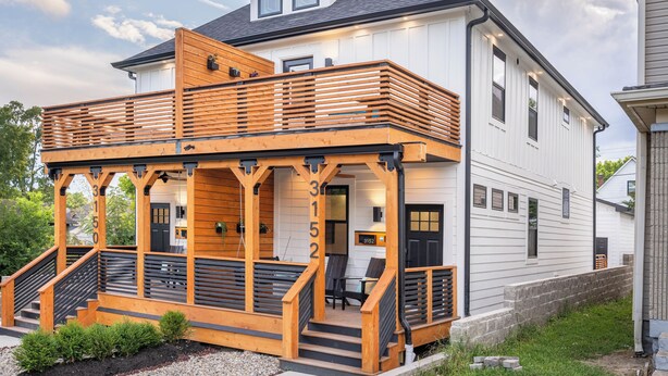 A two-story house with a wooden deck and stairs leading to the entrance. - Artisan Oasis-Hot Tub | Fire Pit 4BD Right Unit (Indianapolis)