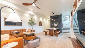 A modern living room with a sofa, coffee table, and a dining area with a table and chairs. - Artisan Oasis-Hot Tub | Fire Pit 4BD Right Unit (Indianapolis)