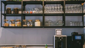 Una zona de cocina con estantes que contienen frascos, vasos y utensilios de cocina.