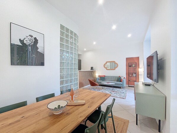 A modern living room with a wooden dining table, a sofa, and a TV.
