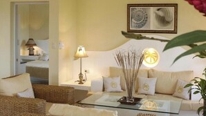 A cozy living room with a sofa, a glass coffee table, a lamp, and a decorative plant. - Presidential Junior Suite - Cabarete (Puerto Plata)
