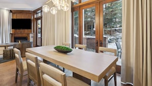 A dining area with a wooden table, chairs, a bowl of greenery, and a fireplace. - The Aspen Mountain Residences 03B (Aspen)