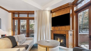 A cozy living room with a fireplace, a round coffee table, and a sofa. - The Aspen Mountain Residences 03B (Aspen)