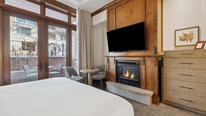 A hotel room with a large bed, a fireplace, a TV, and a view of the outside. - The Aspen Mountain Residences 03C (Aspen)