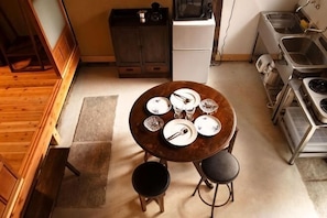 A small kitchen with a round table set for four, a refrigerator, and a stove. - Higashi Matsuyacho East (Kyoto)