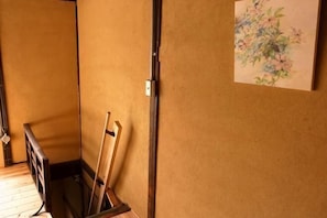 Une pièce avec un plancher en bois, un tableau accroché au mur et une porte dotée d’un cadre noir.
